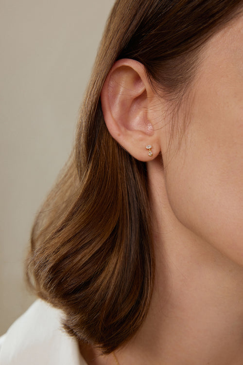 Model trägt filigrane Diamant-Ohrhänger aus 18K Gold mit 0,18 ct Labordiamanten im Oval- und Tropfenschliff