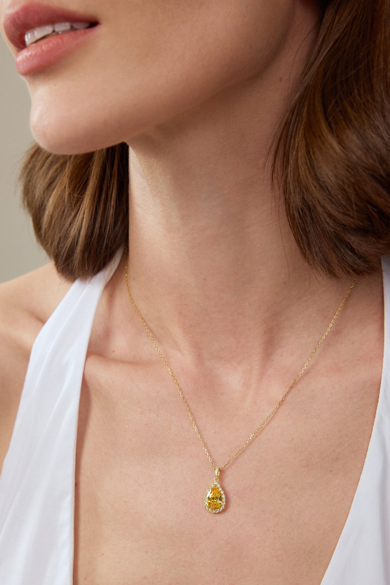Model trägt einen Fancy Yellow Diamantanhänger aus 18K Gold mit 3,50 ct Labordiamanten, tropfenförmigem Mittelstein und Diamant-Halo