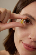 Model hält einen Fancy Yellow Diamantanhänger aus 18K Gold mit 3,50 ct Labordiamanten und tropfenförmigem Mittelstein vor das Auge
