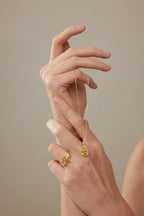 Hand hält eine Kette mit Fancy Yellow Diamantanhänger aus 18K Gold und 3,50 ct Labordiamanten; dazu ein passender Diamantring