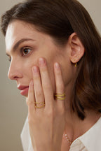 Model trägt einen V-förmigen Ring aus 18K Gold mit 0,35 ct Fancy Yellow Labordiamanten zusammen mit weiteren filigranen Ringen