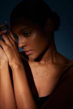 Model trägt eine Initialenkette aus 18K Gold mit diamantbesetztem Buchstaben S und zwei beweglichen Labordiamanten, insgesamt 0,42 ct, im kontrastreichen Licht.