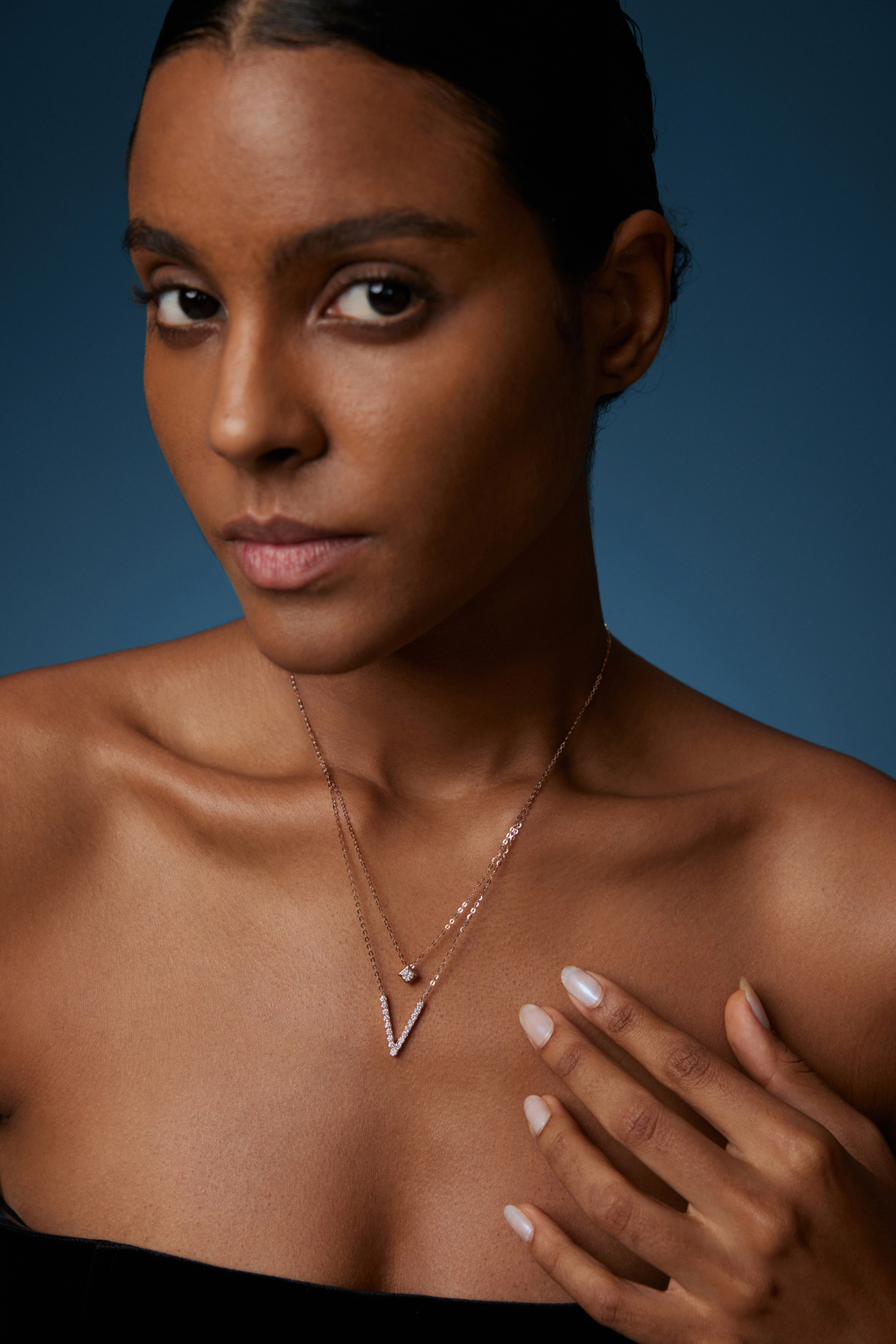 Model trägt eine zweireihige Diamantkette aus 18K Roségold mit diamantbesetztem V-Anhänger und quadratischem Diamantdetail.
