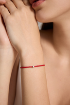 Detailaufnahme eines roten Armbands aus veganem Leder mit 0,10 ct Labordiamant und Fassung aus 18K Gold am Handgelenk