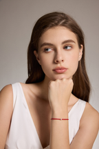 Model trägt ein rotes Armband aus veganem Leder mit 0,10 ct Labordiamant und Fassung aus 18K Gold am Handgelenk