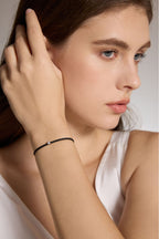 Model trägt ein schwarzes Armband aus veganem Leder mit 0,10 ct Labordiamant und Fassung aus 18K Gold am Handgelenk