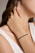 Detailaufnahme eines schwarzen Armbands aus veganem Leder mit 0,10 ct Labordiamant und Fassung aus 18K Gold am Handgelenk