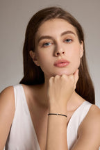 Model trägt ein schwarzes Armband aus veganem Leder mit 0,10 ct Labordiamant und Fassung aus 18K Gold am Handgelenk