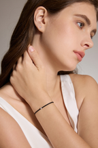 Model trägt ein schwarzes Armband aus veganem Leder mit 0,10 ct Labordiamant und Fassung aus 18K Gold am Handgelenk