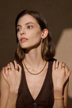 Model trägt ein skulpturales Glieder Collier aus massivem 18K Gold kombiniert mit mehreren Goldringen und einem Armband.